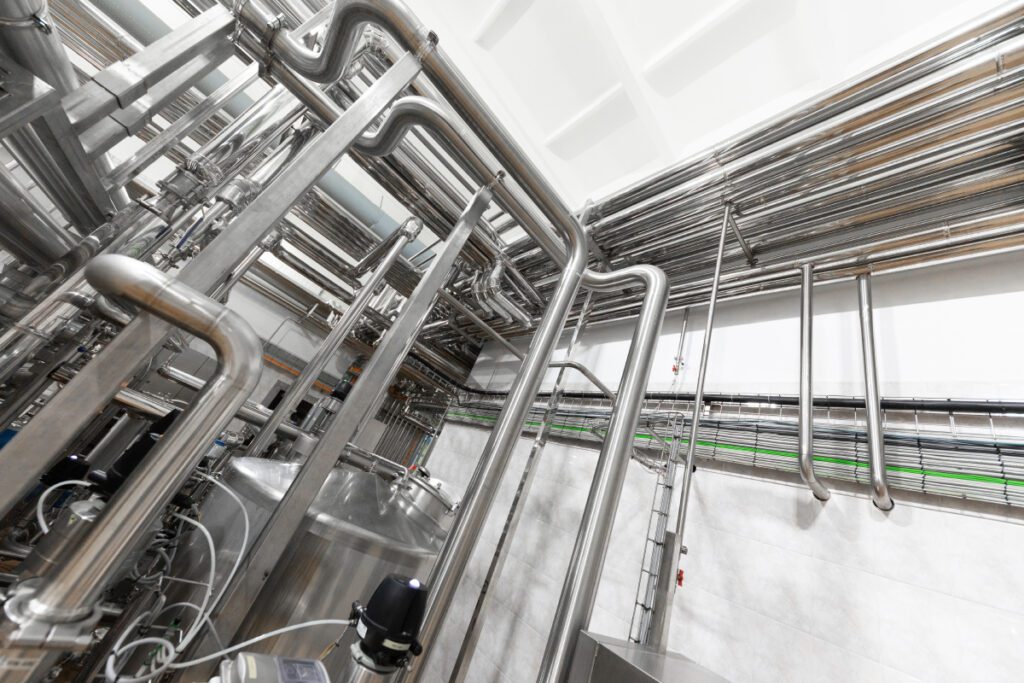 Steel water pipeline chrome pipes pipe lines in plant workshop. Industrial background Coastal Resources Group