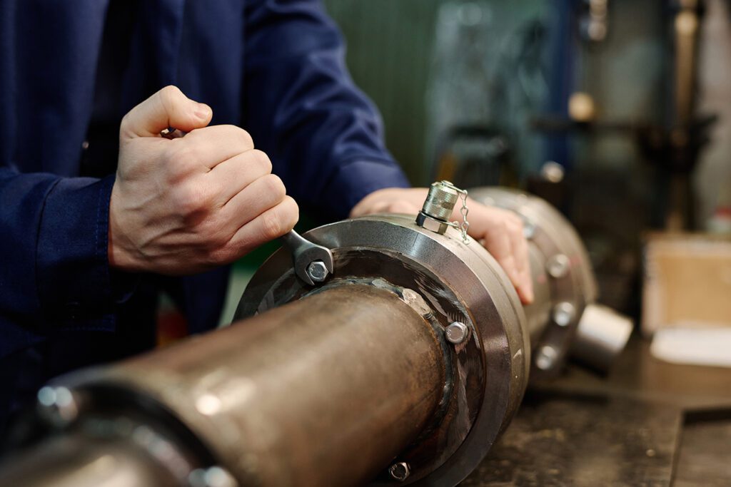 unrecognizable man repairing machine part Coastal Resources Group